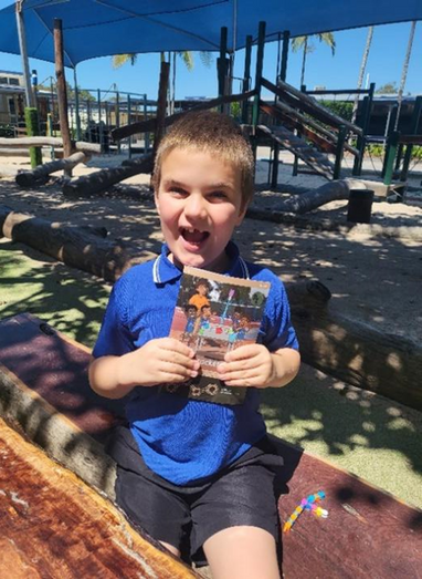 A photo of Billings looking very excited with his book at the playground