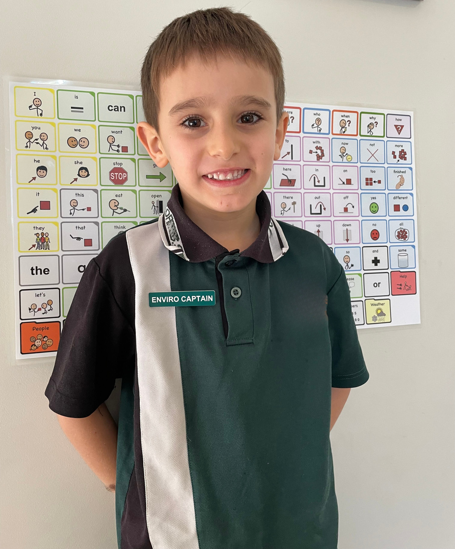 Photo of Darcy in his school uniform in front of a printed vocabulary board