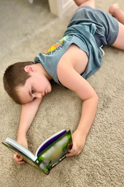 Photo of Billings at home lying on the floor reading